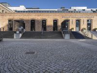 an empty courtyard with stairs and steps in front of it and a brick building behind it