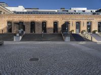 an empty courtyard with stairs and steps in front of it and a brick building behind it