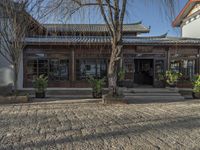 there is a courtyard in china outside an older building and a tree in front of it