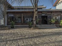 there is a courtyard in china outside an older building and a tree in front of it