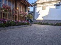 a courtyard area with flowering plants and bikes parked on the side walk at dusk,