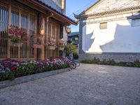 a courtyard area with flowering plants and bikes parked on the side walk at dusk,