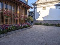 a courtyard area with flowering plants and bikes parked on the side walk at dusk,