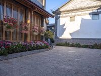 a courtyard area with flowering plants and bikes parked on the side walk at dusk,