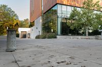 the courtyard features concrete, plants and a fire hydrant surrounded by trees and glass windows