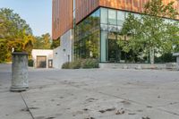 the courtyard features concrete, plants and a fire hydrant surrounded by trees and glass windows