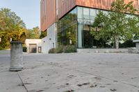 the courtyard features concrete, plants and a fire hydrant surrounded by trees and glass windows