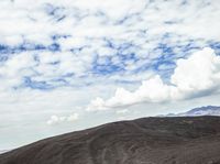 a cow is standing on top of a hill under cloudy skiess looking into the distance