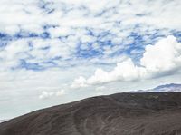 a cow is standing on top of a hill under cloudy skiess looking into the distance