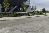 the asphalt is cracked and in between a building and trees on either side of the building