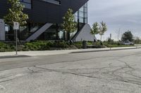 the asphalt is cracked and in between a building and trees on either side of the building