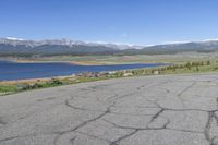 the intersection has patches of cracks in concrete and a view of mountains, lake, and town