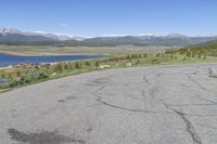 the intersection has patches of cracks in concrete and a view of mountains, lake, and town