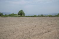 an empty area with some trees in the distance and mountains in the distance through it