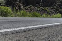 an asphalt road with a motorcycle in the middle of it next to a steep mountain