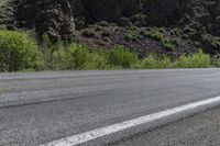 an asphalt road with a motorcycle in the middle of it next to a steep mountain