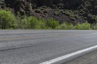 an asphalt road with a motorcycle in the middle of it next to a steep mountain