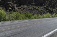 an asphalt road with a motorcycle in the middle of it next to a steep mountain