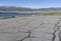 a car that is parked in a parking lot next to a lake with mountains in the background