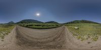 a dirt bike jump on an empty road with mountains in the back ground and green fields in the distance