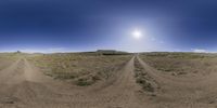 a panorama - like image of a dirt road and dirt mounds in the distance, with a bright light shining overhead