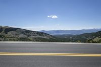 a lone road running along the mountain side in front of some beautiful mountainside view