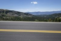 a lone road running along the mountain side in front of some beautiful mountainside view