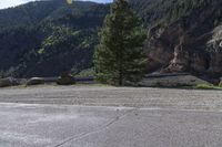 two motorcycles are stopped near the water and mountains in the background with trees, rocks, gravel path and riverbank