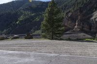 two motorcycles are stopped near the water and mountains in the background with trees, rocks, gravel path and riverbank