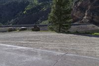 two motorcycles are stopped near the water and mountains in the background with trees, rocks, gravel path and riverbank