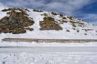 a lone cross country skier skis along a mountain side as the tide hits on the edge