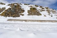 a lone cross country skier skis along a mountain side as the tide hits on the edge