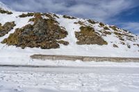 a lone cross country skier skis along a mountain side as the tide hits on the edge