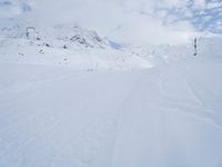 a cross country skier is traveling down a snowy slope in the mountains to ski on