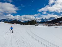 person cross country skiing on snowy terrain with mountains in the background for use as backdrop