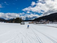 person cross country skiing on snowy terrain with mountains in the background for use as backdrop