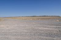 a dirt road runs through an open plain area with no vegetation on it, in the background is a sky with low clouds