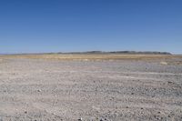 a dirt road runs through an open plain area with no vegetation on it, in the background is a sky with low clouds