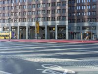 a street in front of an office building and a bicycle lane, with a bus parked next to it