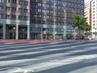 a street in front of an office building and a bicycle lane, with a bus parked next to it