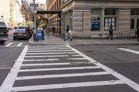 a white crosswalk next to some people walking down the street with a car and taxi