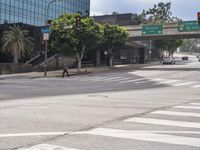 a crosswalk and pedestrian crossing on a street next to a freeway bridge and some tall buildings