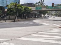 a crosswalk and pedestrian crossing on a street next to a freeway bridge and some tall buildings