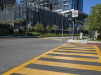 a crosswalk with traffic lights, two cars on the road, and buildings in the background