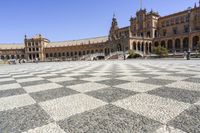 a crowd is walking around in the courtyard of an ornate building with circular patterns on stone flooring