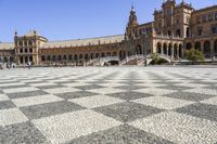 a crowd is walking around in the courtyard of an ornate building with circular patterns on stone flooring