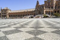 a crowd is walking around in the courtyard of an ornate building with circular patterns on stone flooring