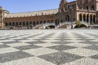 a crowd is walking around in the courtyard of an ornate building with circular patterns on stone flooring