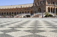 a crowd is walking around in the courtyard of an ornate building with circular patterns on stone flooring