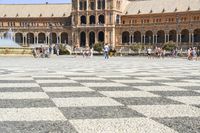 a crowd is walking around in the courtyard of an ornate building with circular patterns on stone flooring